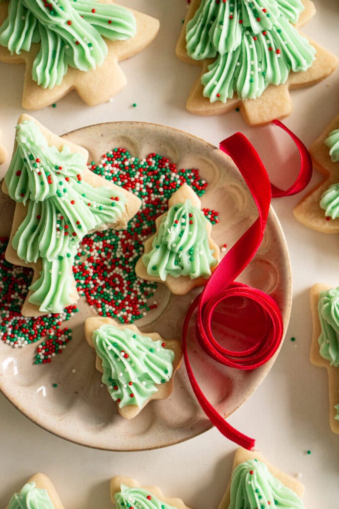 small saucer filled with red and green sprinkles with frosted sugar cookies and ribbon