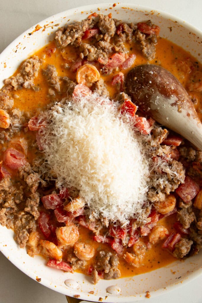 Sauté pan with Shrimp, sausage, tomatoes, and cream sauce topped with shredded parmesan cheese.