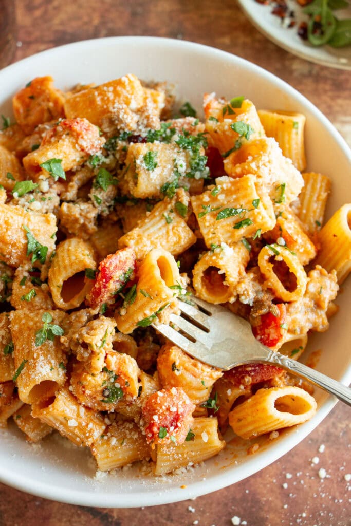 Serving bowl full of rigatoni with spicy Cajun sauce and parmesan cheese