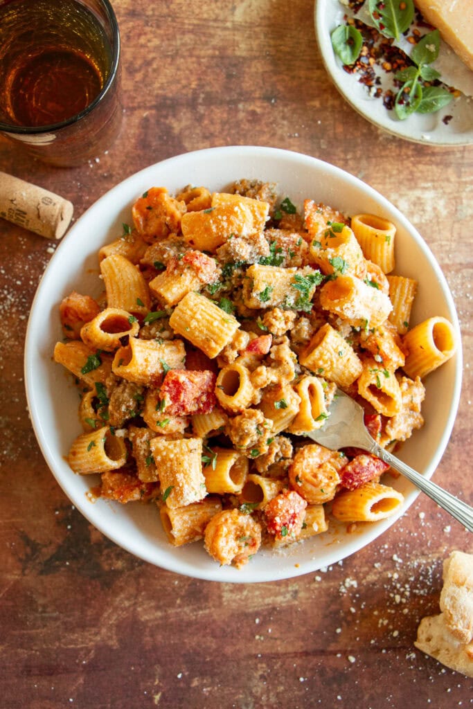 Large bowl of Cajun shrimp pasta with fresh parsley and a glass of wine. 