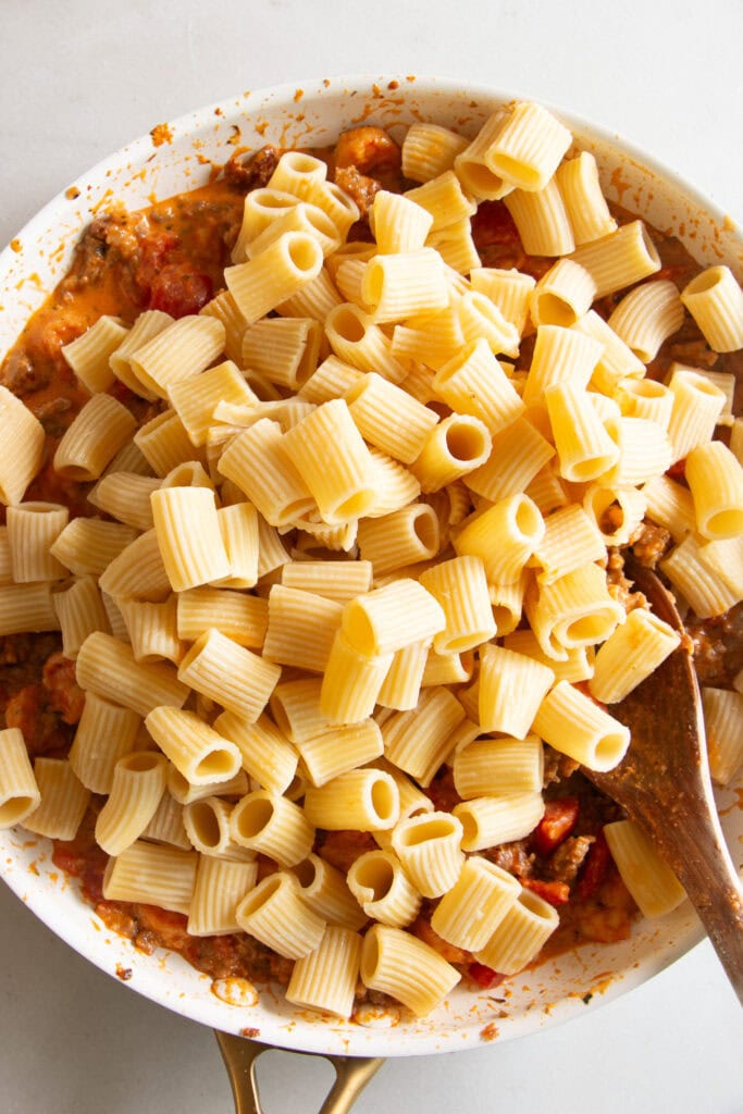 Cooked pasta added into the pasta sauce in the sauté pan