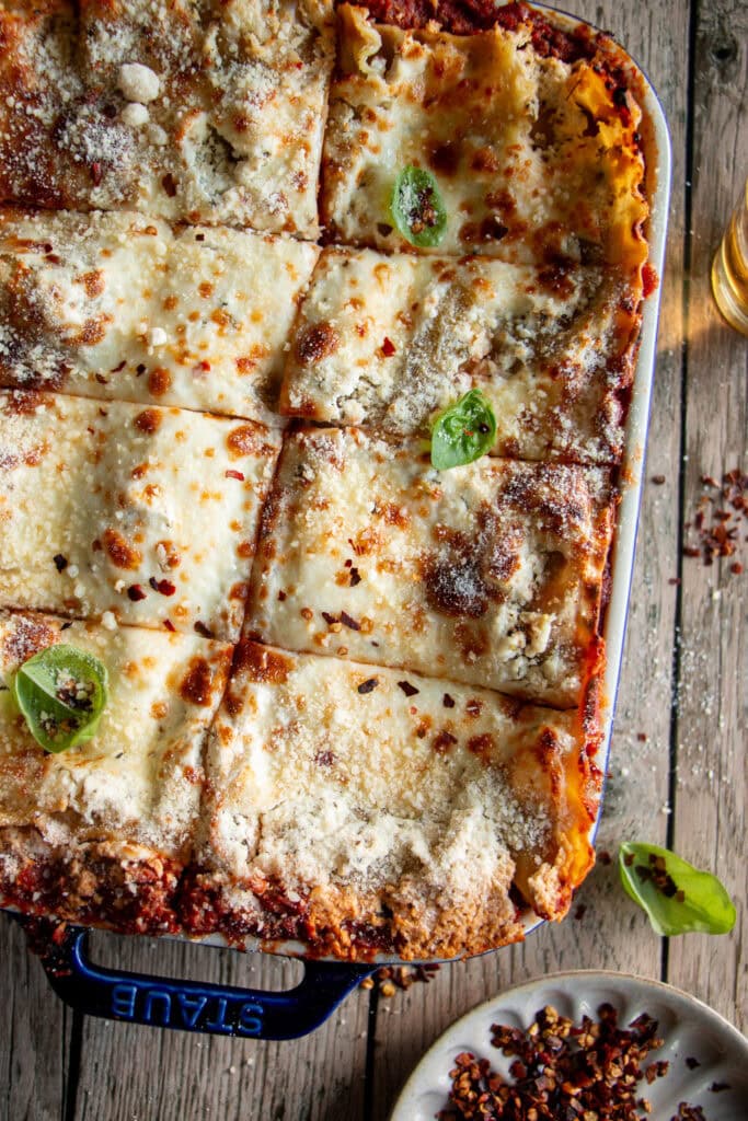 a rectangle baking dish with fresh baked lasagna that has been sliced and topped with fresh basil.