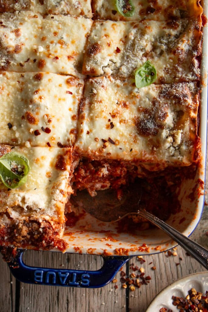 A large casserole pan full of lasagna with a slice removed