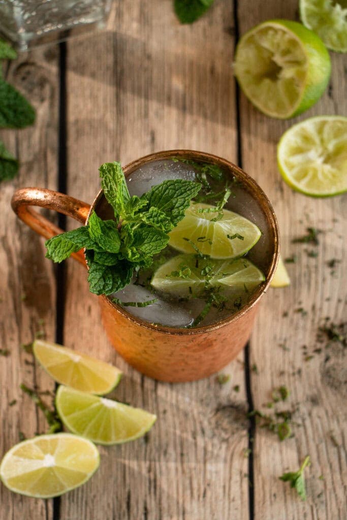 Overhead shot of a fresh made, chilled Moscow mule with gin topped with lime wedges and mint.