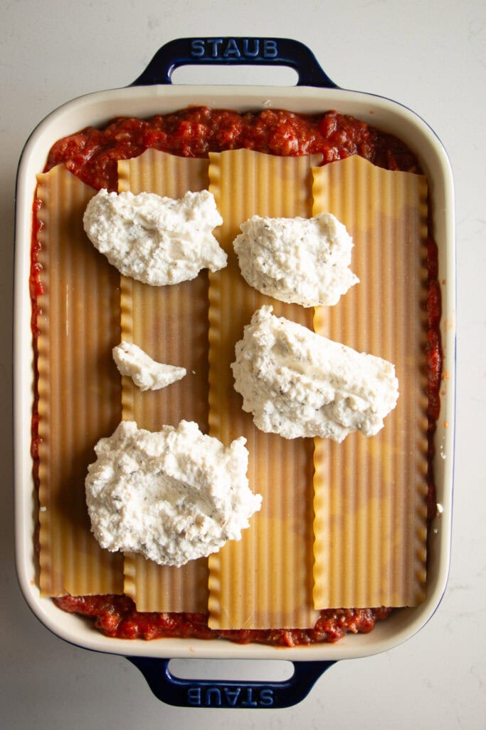 casserole dish with sauce, lasagna noodles, and ricotta