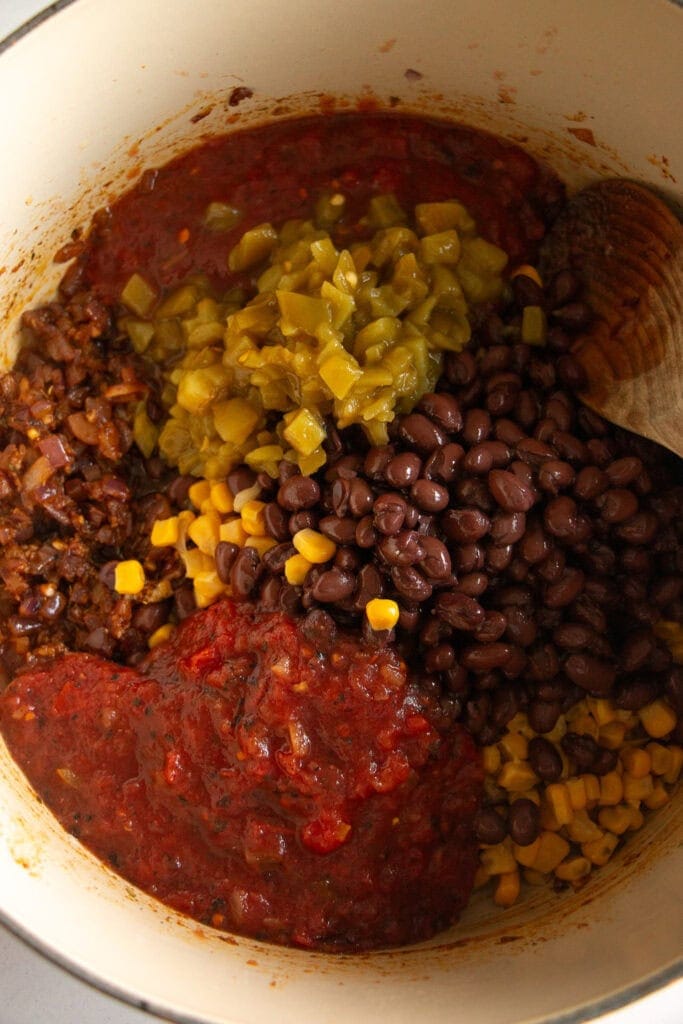 Dutch oven full of roasted tomatoes, black beans, corn, chilis, and sauteed onions