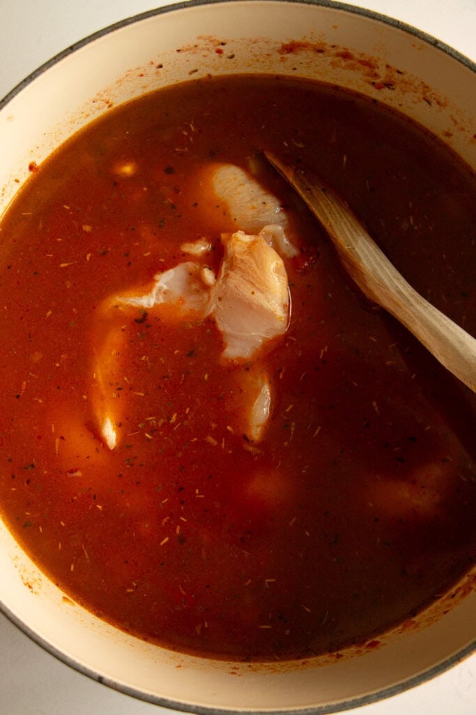 Soup liquid in a Dutch oven with raw chicken