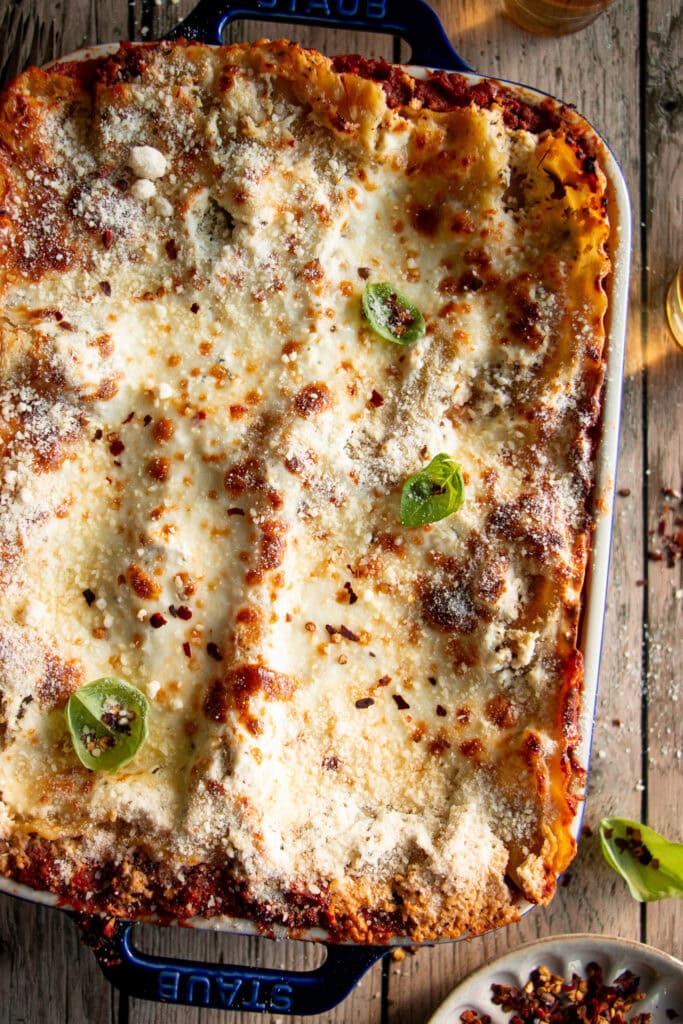 Large blue casserole dish loaded with layered lasagna and topped with a bubbly cheese mixture