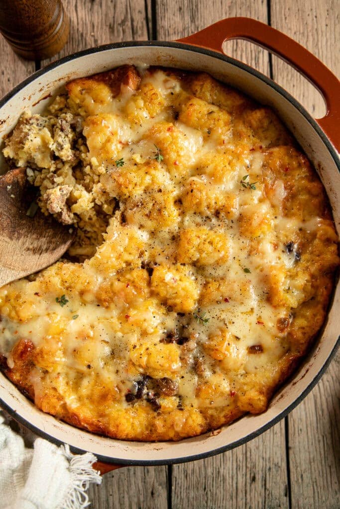 fresh baked egg casserole with gooey cheese on top and a spoon taking a scoop out.