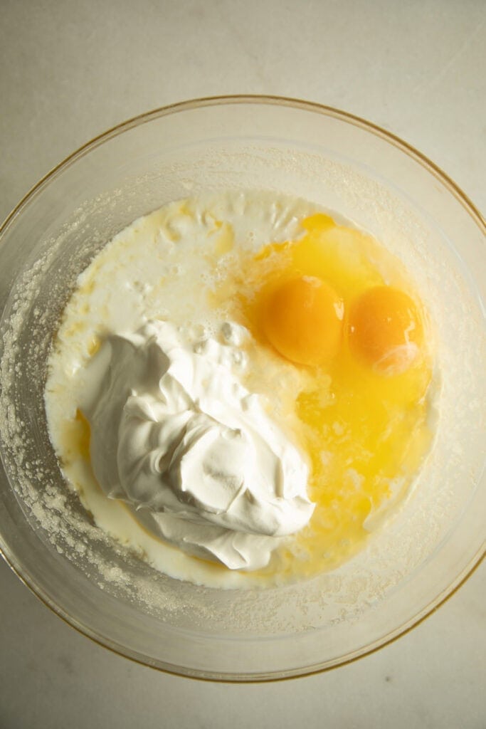 Mixing bowl with sugar mixture, eggs, and sour cream. 
