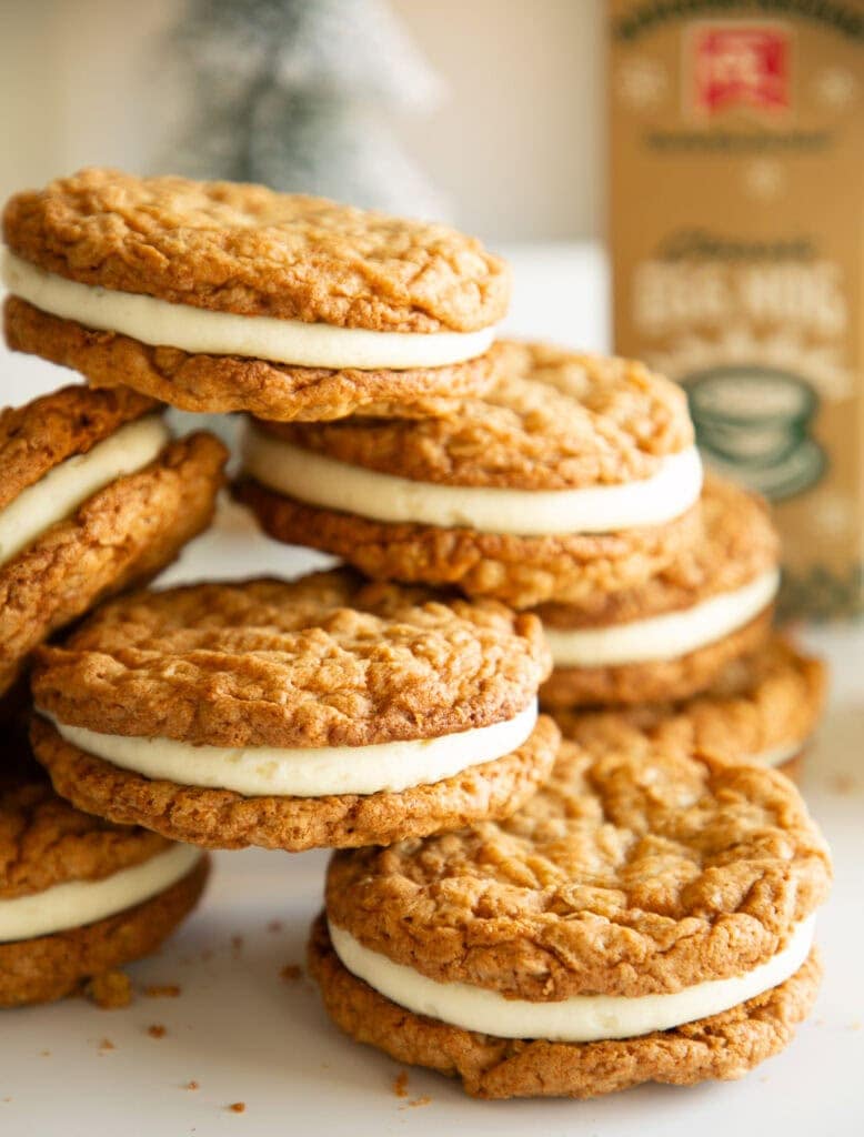Stacked egg nog cookies with frosting and a glass of egg nog