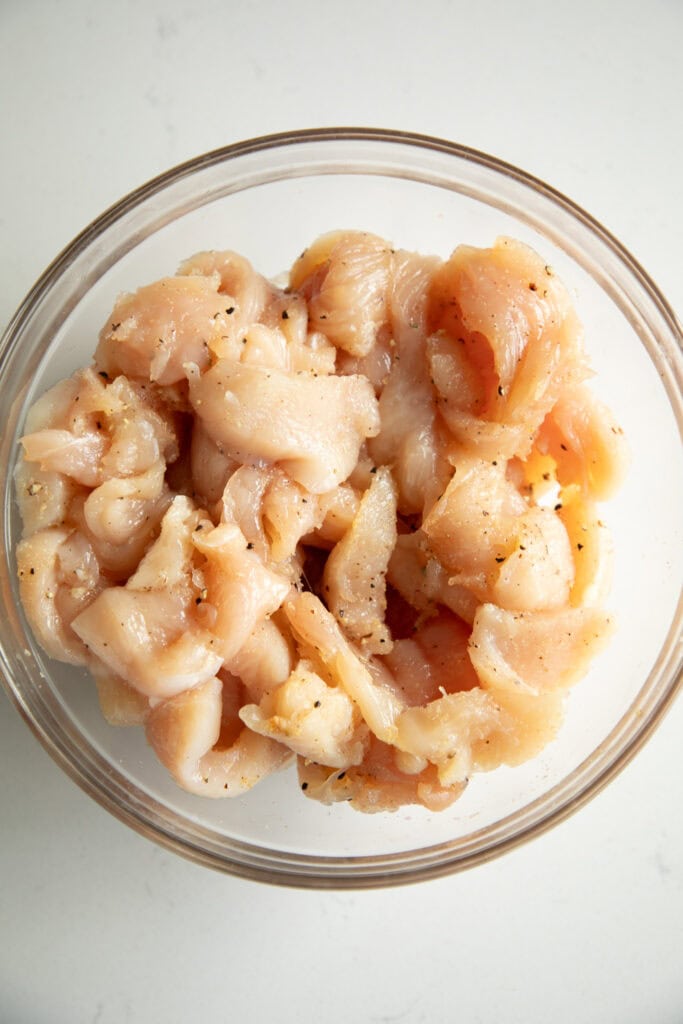 Cubed chicken in a mixing bowl with salt and pepper