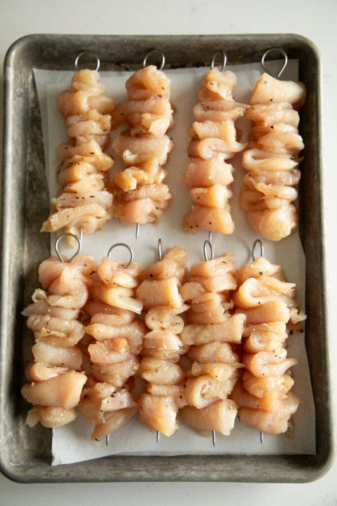 skewered seasoned chicken pieces on a sheet pan
