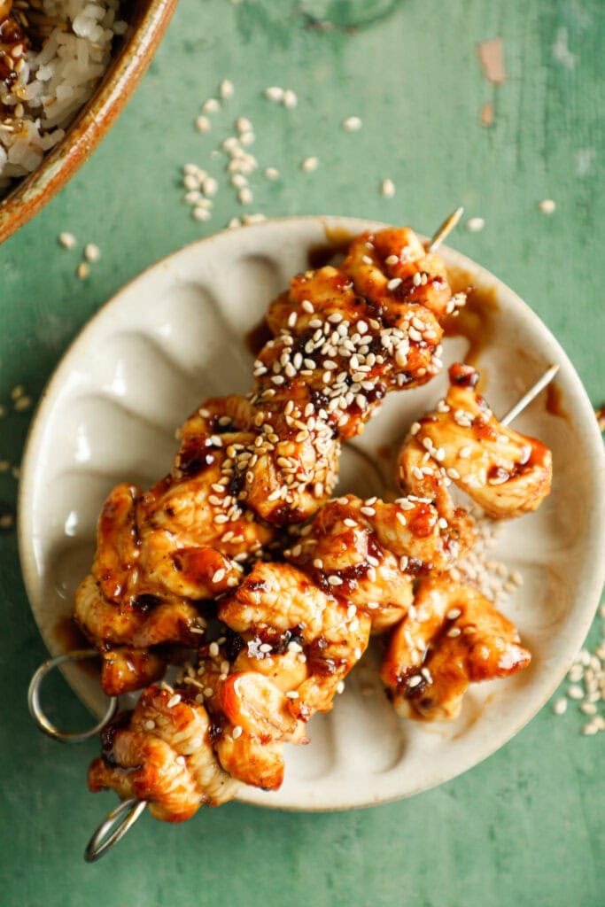 Two teriyaki chicken skewers on a plate
