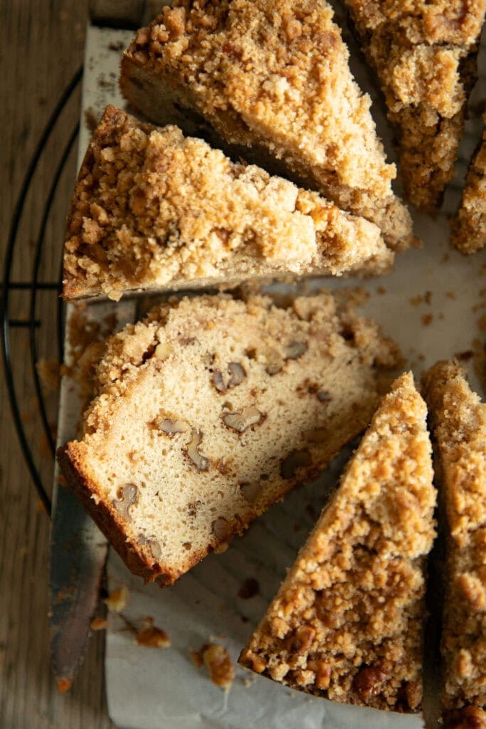 Slices of walnut coffee cake on a wire rack, one side ways slice showing chunks of walnuts