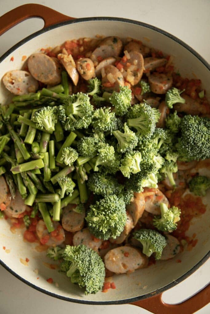 fresh broccoli and asparagus added into the pan with the sausage and sauteed veggies