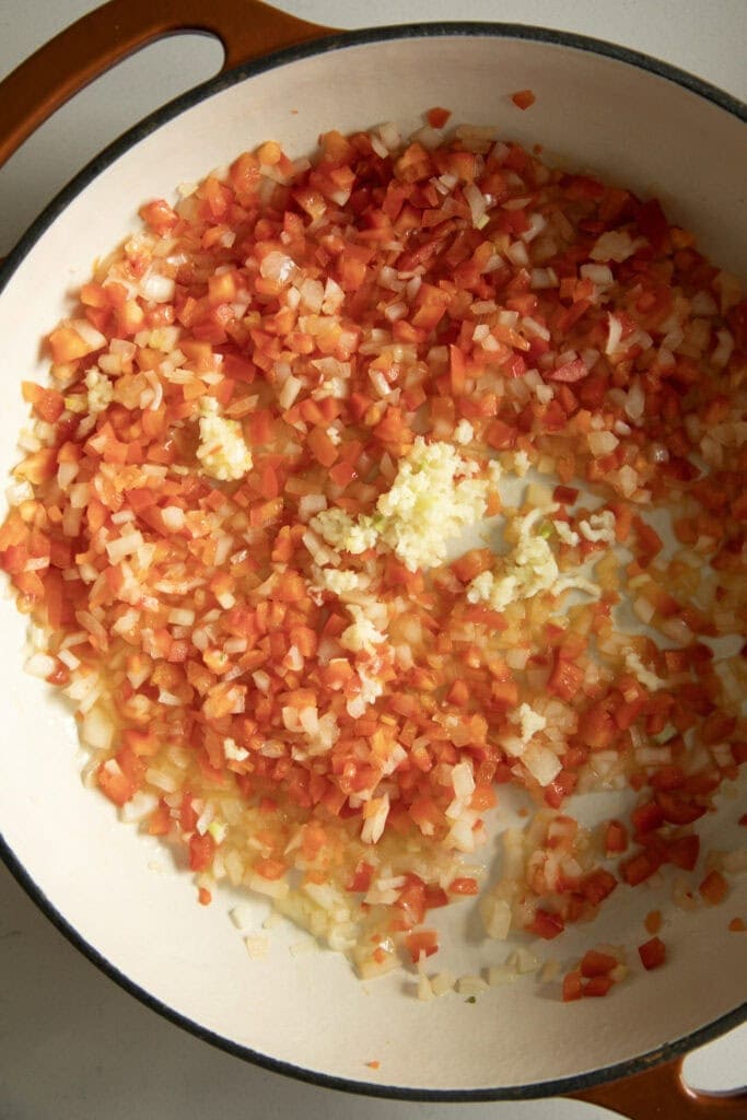 Large pan with sauteed onion, garlic, and bell pepper.