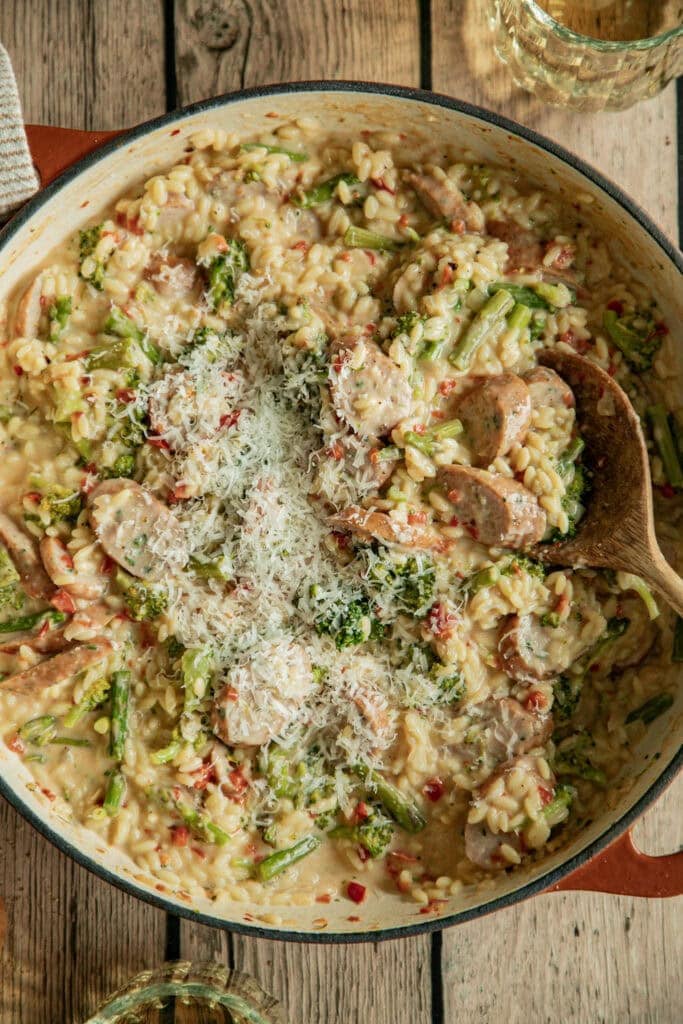 large skillet full of orzo with veggies and sausage