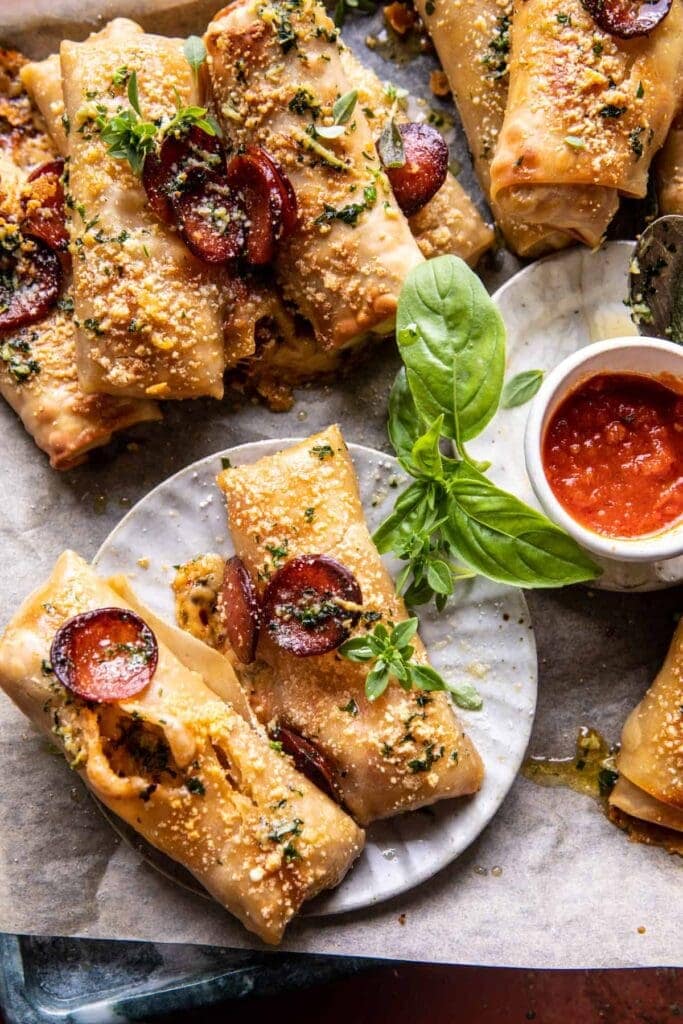 Pizza egg rolls on parchment paper with garlic butter