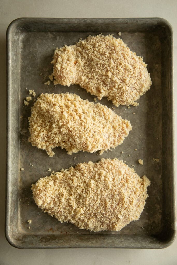 coated chicken cutlets on a sheet pan 