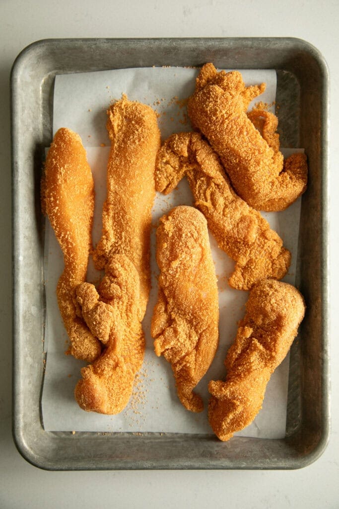 Coated chicken tenders on a sheet pan