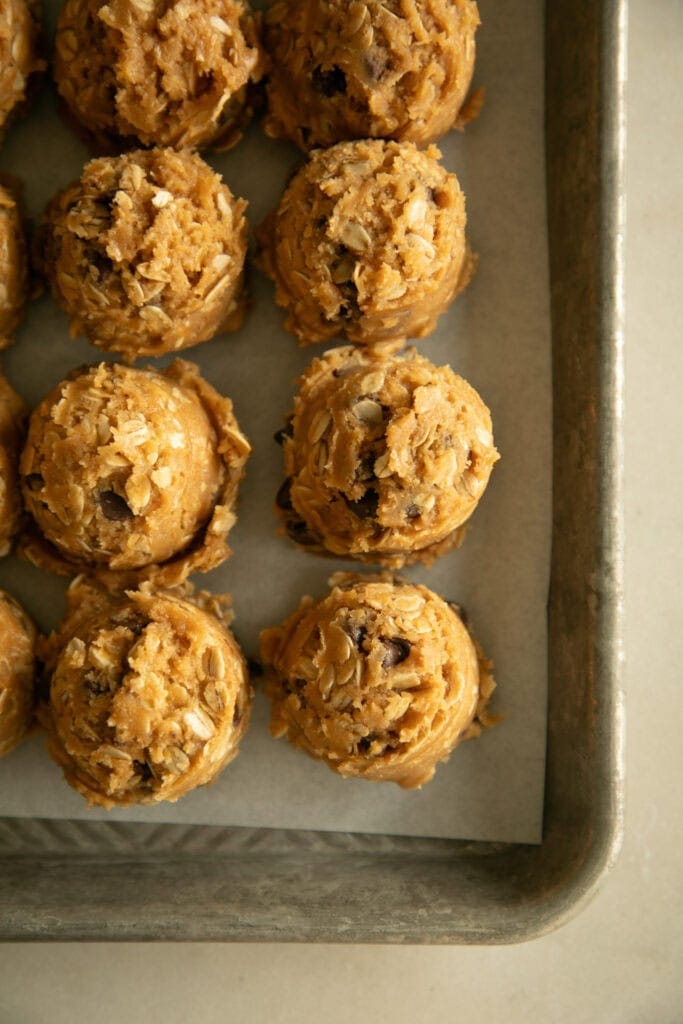scoops of cookie dough on a lined sheet pan