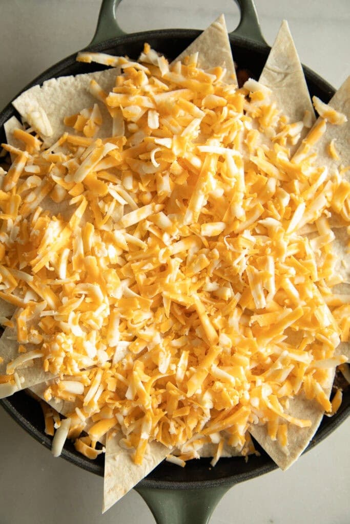 skillet topped with tortillas and shredded cheese