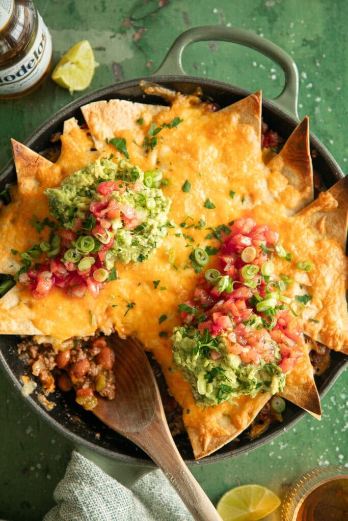 Skillet full of taco casserole with a scooped taken out.