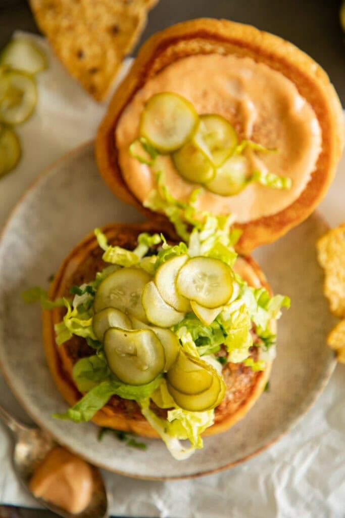 open faced chicken burger on a bun with fresh pickles