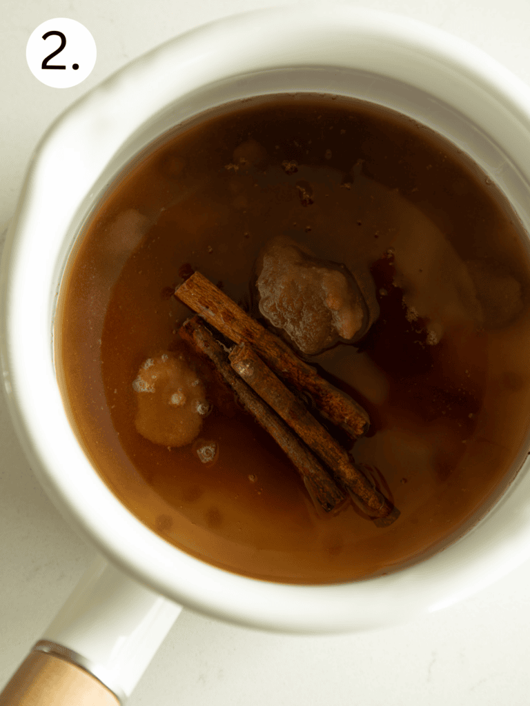 sugar, water, and cinnamon sticks combined in a sauce pan