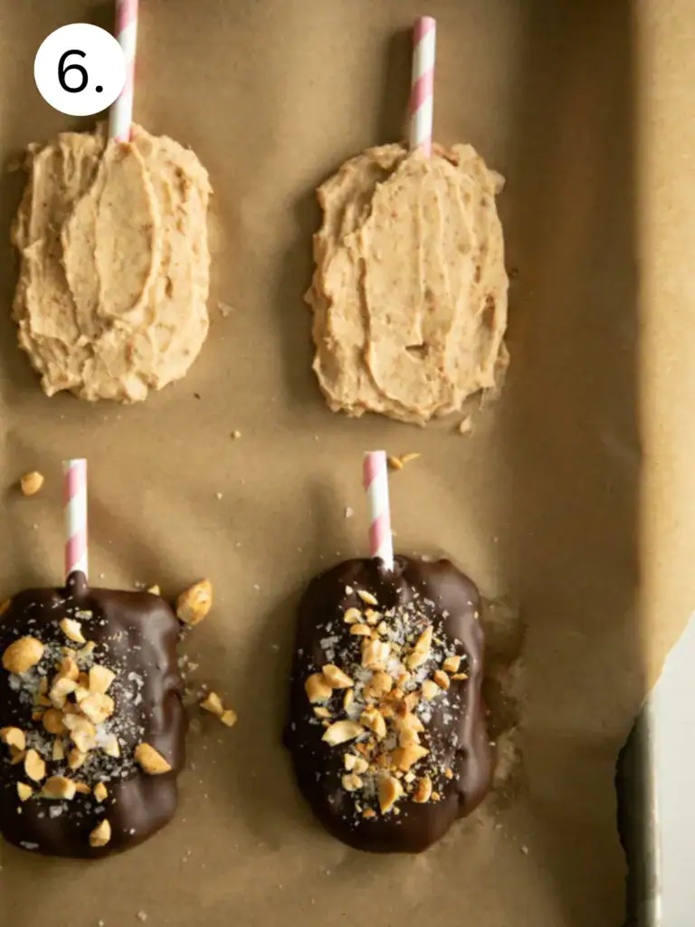 Frozen buster bars dipped in chocolate on a piece of parchment