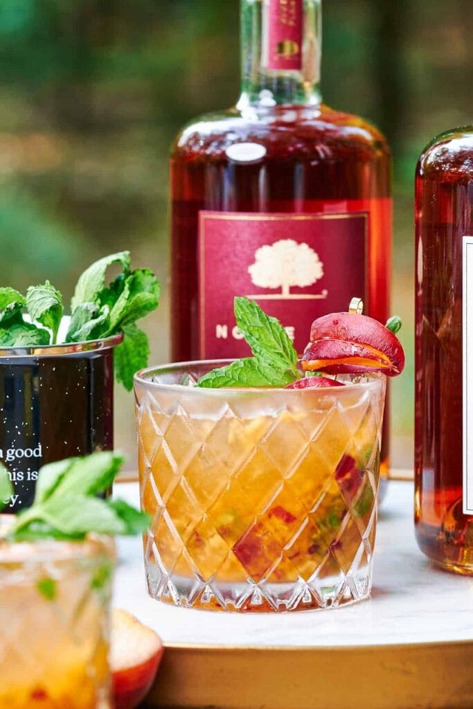 Peach whiskey cocktail with fresh peach slices and fresh mint