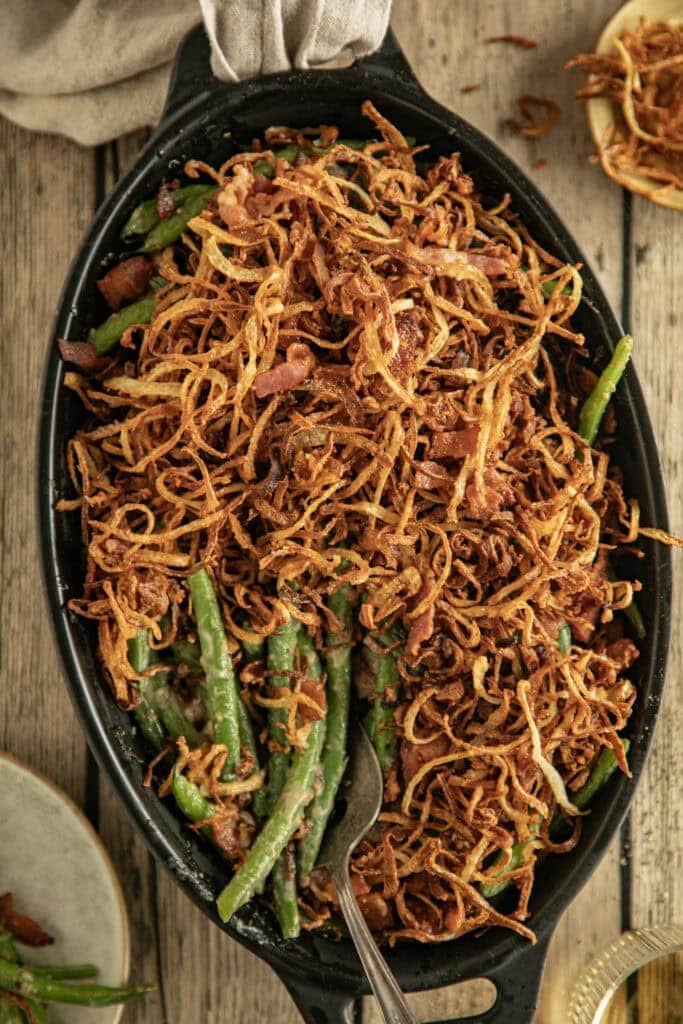 Oval casserole dish with green bean casserole topped wit homemade crispy onions 