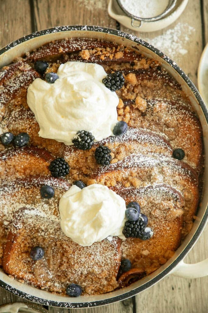 Round casserole pan with baked Bailey's French toast topped with fresh whipped cream and berries