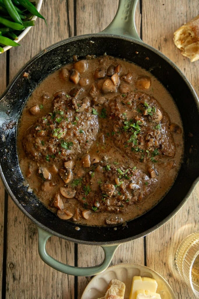 Pan fried cube steaks in a large skillet with brown pan sauce