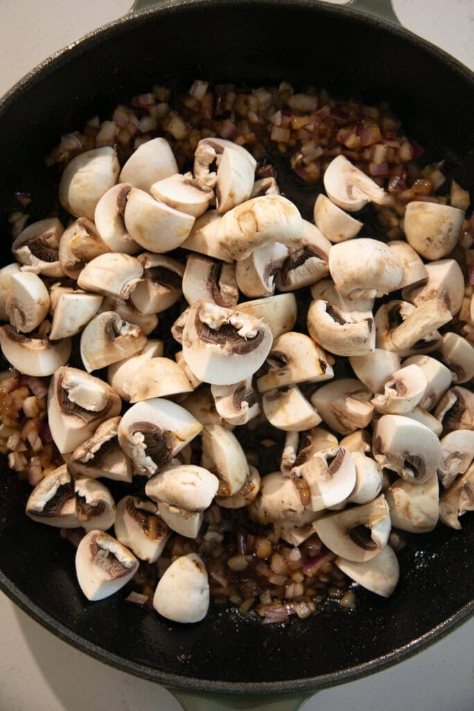 cast iron pan with onion and chopped mushrooms