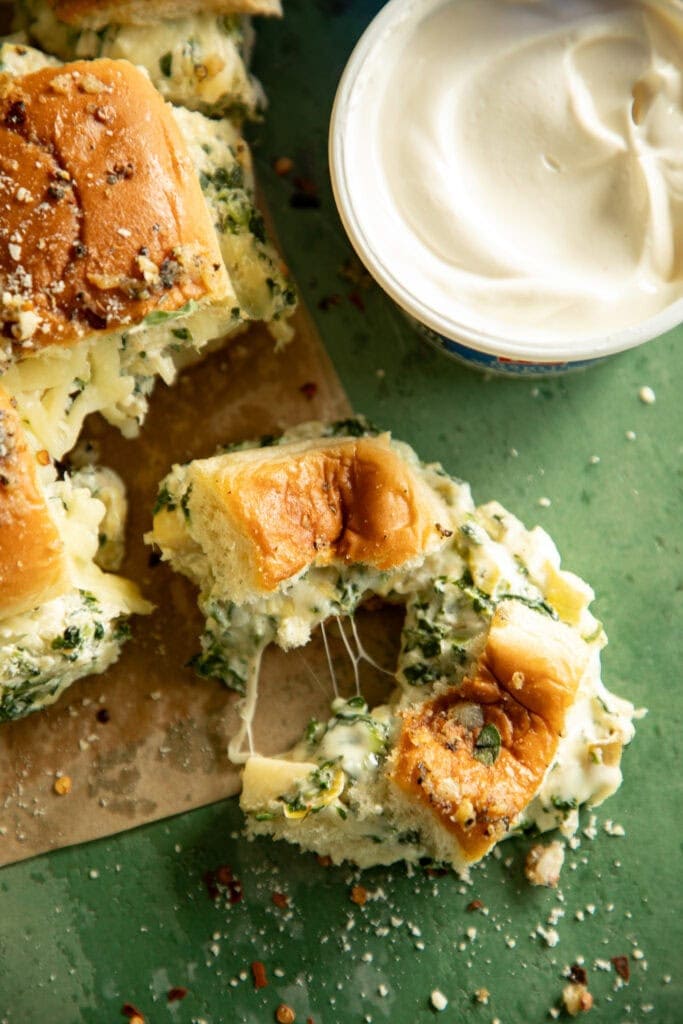 A fresh baked gooey spinach dip slider torn in half