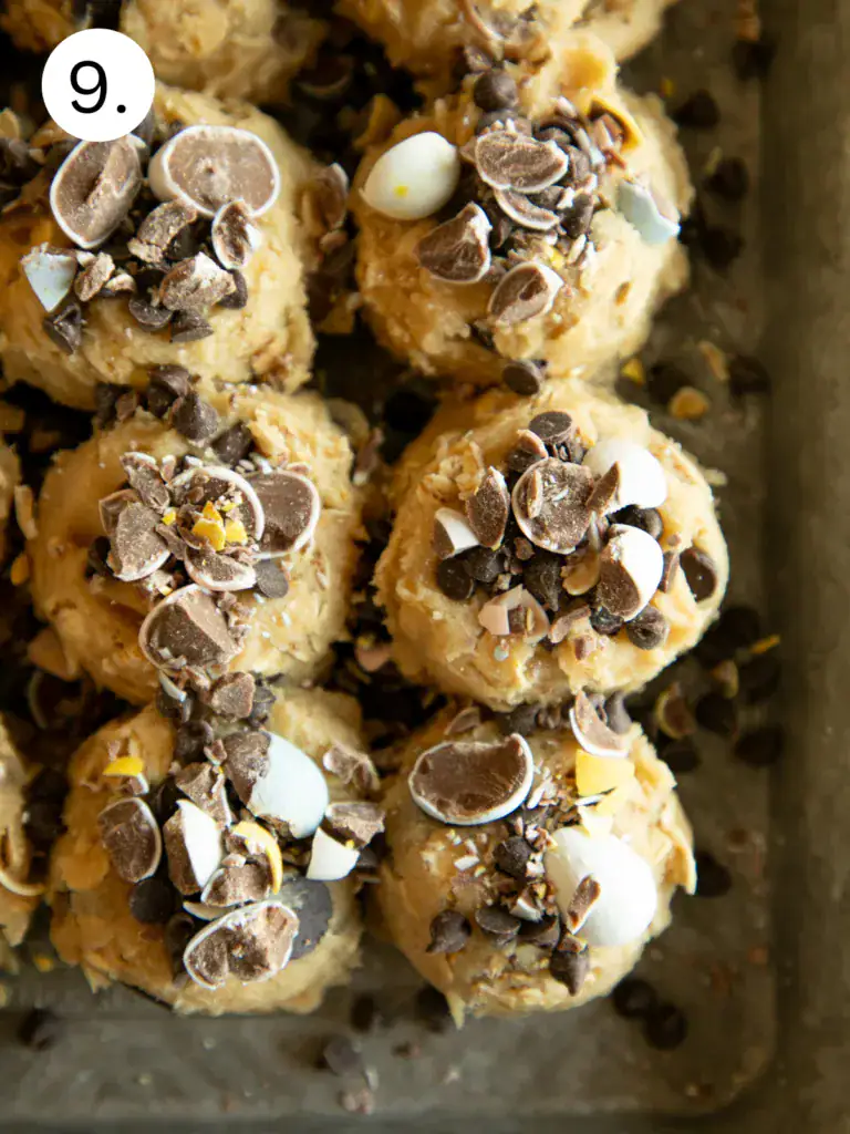 Sheet pan with cookie dough scoops topped with crushed candy eggs