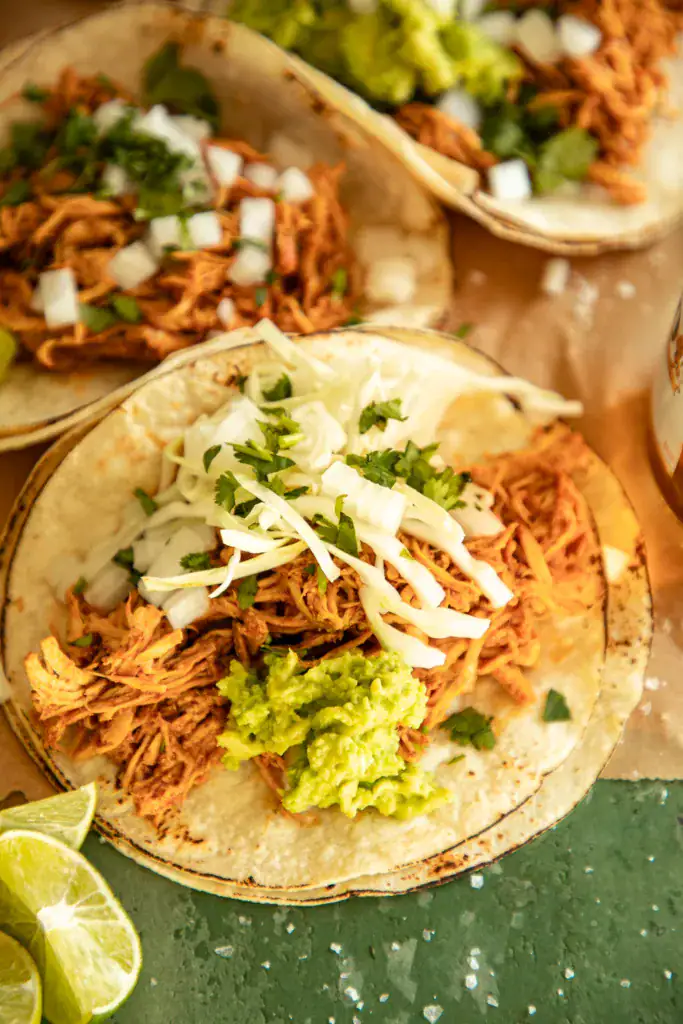 charred corn tortillas topped with instant pot chicken, cilantro, and guacamole 