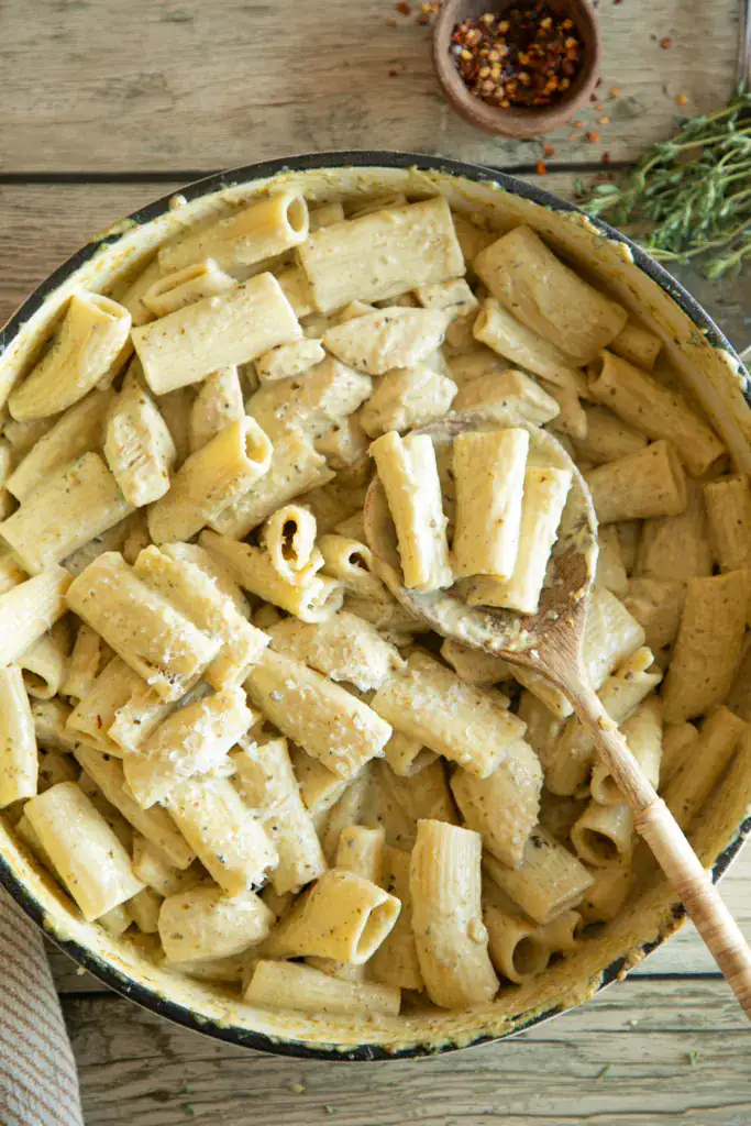 Large Dutch oven full of chicken pesto pasta with shredded parmesan cheese