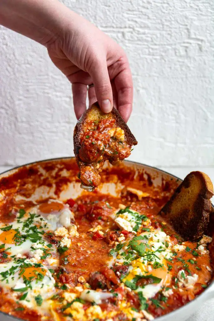baked eggs in a casserole dish with a piece of bread 