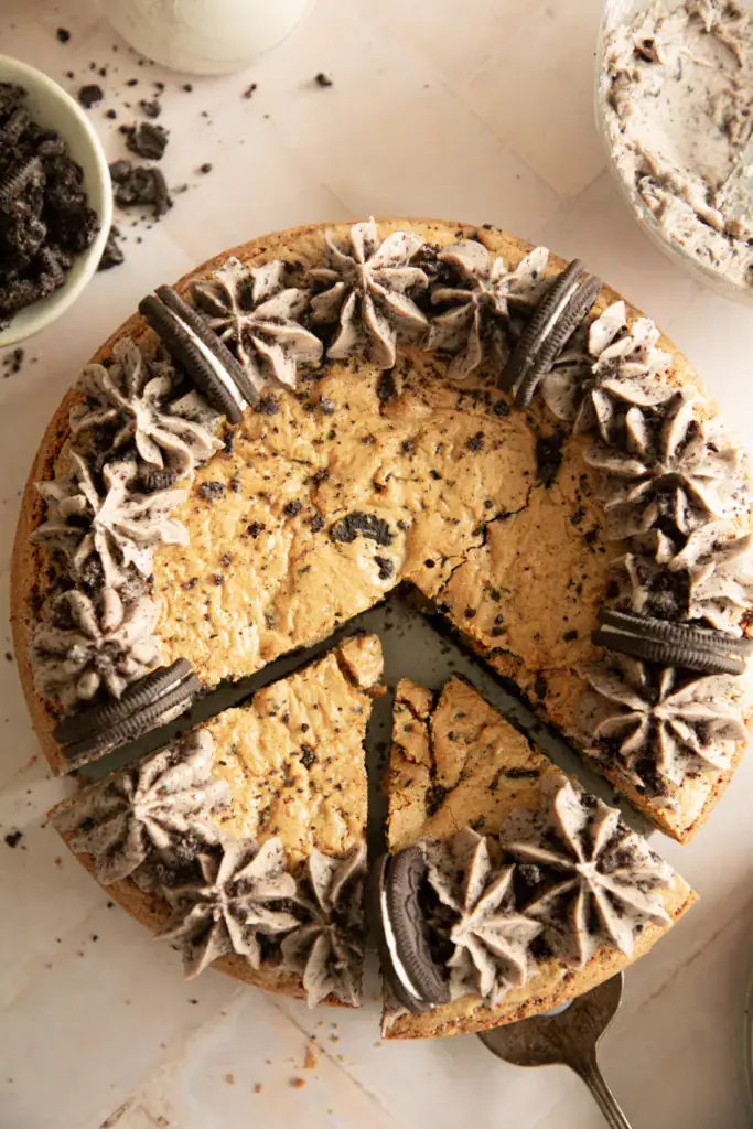 Round cookie cake with 2 slices cut topped with Oreo buttercream frosting