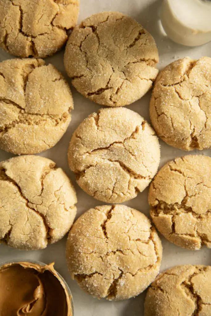 Close-up of soft and chewy peanut butter cookies with a glass of milk and a bowl of peanut butter