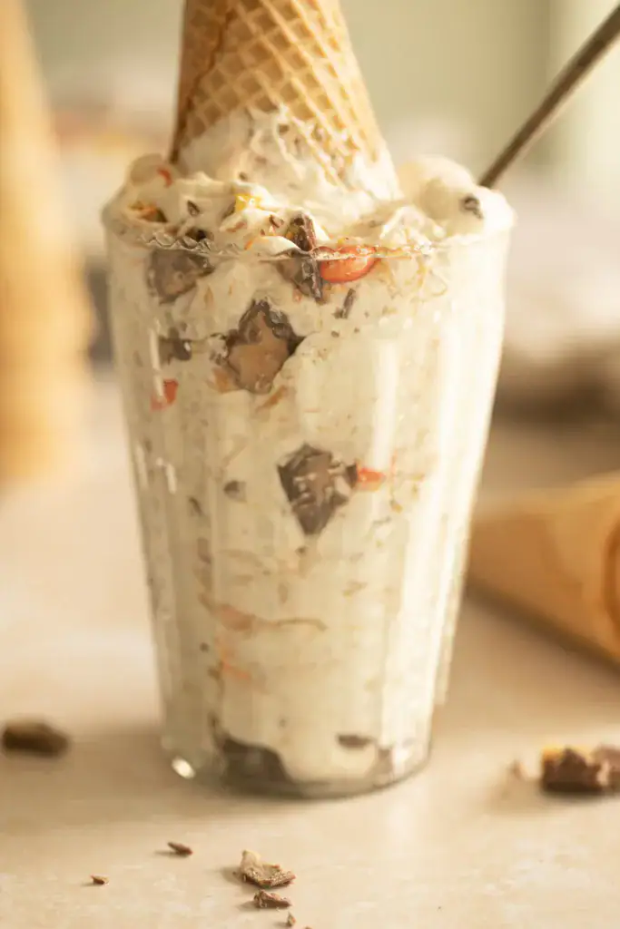 Glass full of peanut butter cup ice cream with a sugar cone inside