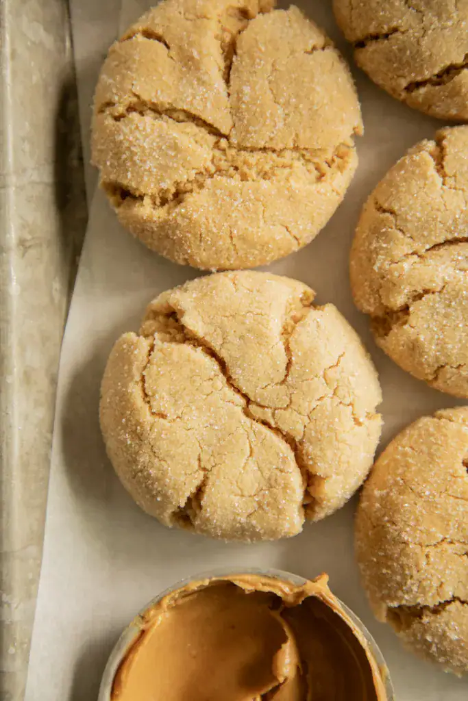 Cracked-top peanut butter cookies next to a small dish of creamy peanut butter