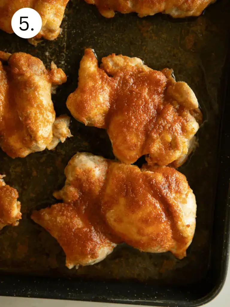 Cooked and broiled chicken thighs on baking sheet