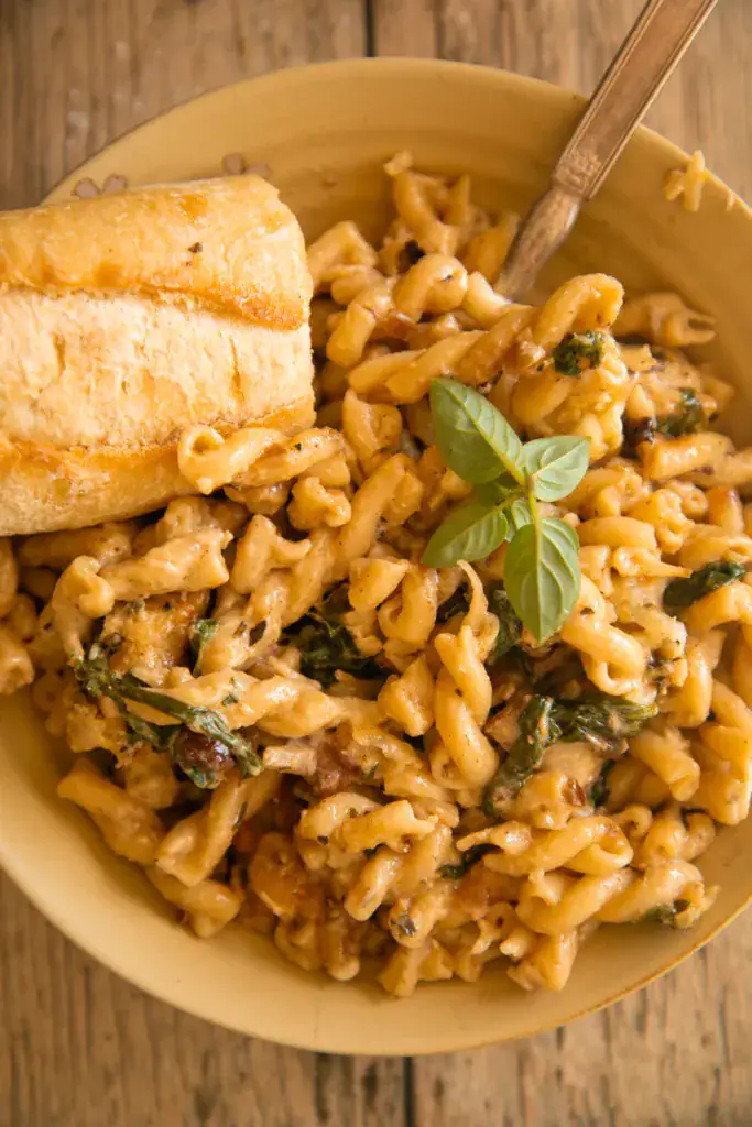 Creamy chicken spinach pasta served in a bowl with crusty bread and fresh basil garnish.