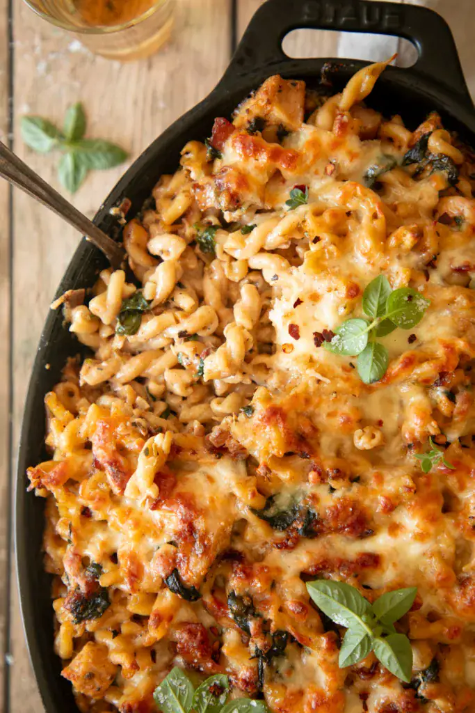 Baked chicken bacon spinach pasta in a Staub dish, golden and bubbly with melted cheese on top.