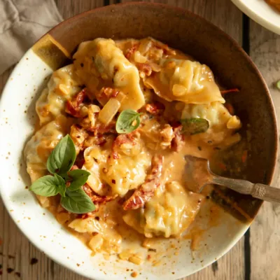 Bowl of baked dumplings with a fork resting inside, coated in a creamy tomato-basil sauce.