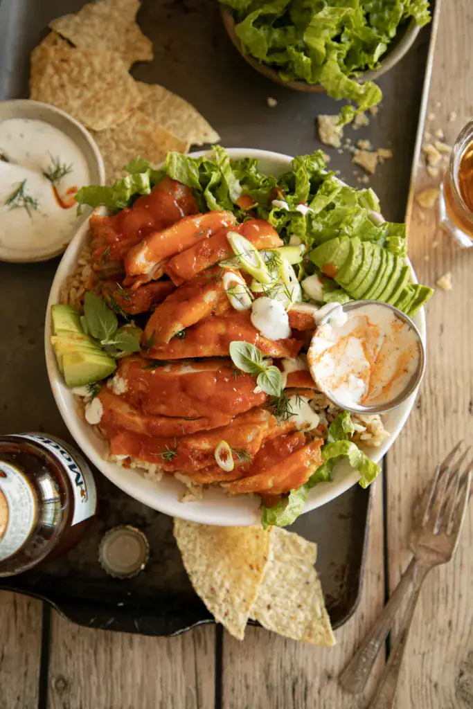 Overhead of buffalo chicken bowl with lettuce, avocado, and ranch